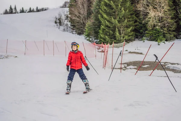 Child skiing in mountains. Active toddler kid with safety helmet, goggles and poles. Ski race for young children. Winter sport for family. Kids ski lesson in alpine school. Little skier racing in snow — Stock Photo, Image