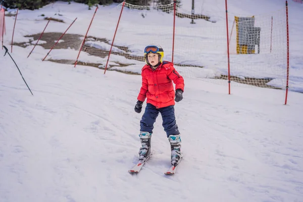 Дитячі лижі в горах. Активний малюк з шоломом безпеки, окулярами та полюсами. Катання на лижах для маленьких дітей. Зимовий спорт для сім'ї. Дитячий гірськолижний урок у гірськолижній школі. Маленькі гонки на лижах у снігу — стокове фото