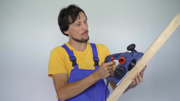 Een man professionele tegel installateur een houten plank en een elektrische schaafmachine in zijn handen. Hij kijkt glimlachend naar de camera. — Stockvideo