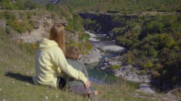 Un disparo de mano de una joven y su hijo que están visitando el cañón del río Moracica en Montenegro. Viajes a Montenegro concepto — Vídeos de Stock