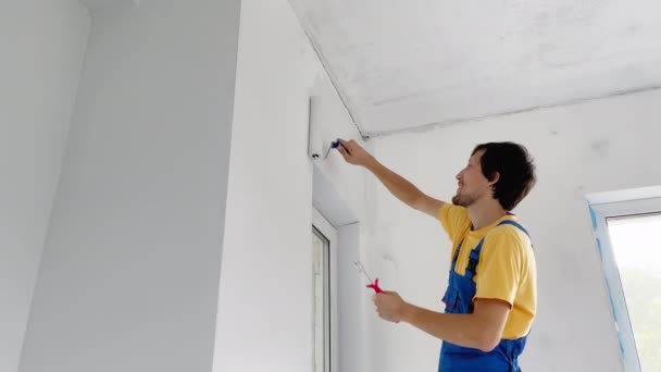 Un trabajador de la construcción profesional hombre pintar la pared con un pintor de rodillos. Disparo en cámara lenta — Vídeos de Stock