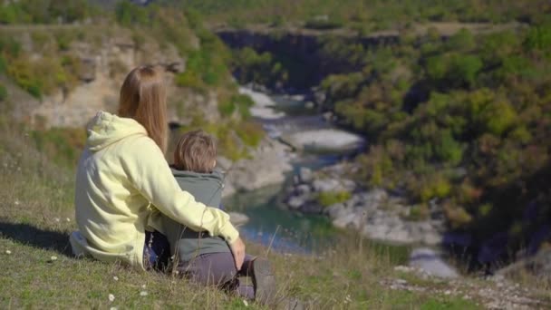 Um tiro de mão de uma jovem e seu filho que estão visitando o desfiladeiro do rio Moracica em Montenegro. Viajar para Montenegro conceito — Vídeo de Stock