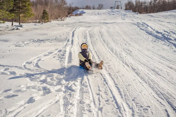 Mulher feliz se divertindo durante rolar pela encosta da montanha no trenó. Esportes de inverno com neve. Pessoas montando um trenó — Fotografia de Stock