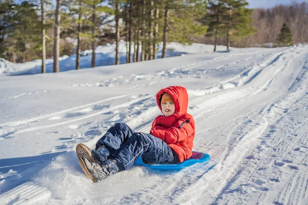 Fröhlicher und positiver kleiner Junge genießt Rodeln und Kälte im Freien, Winterspaß-Aktivitätskonzept — Stockfoto