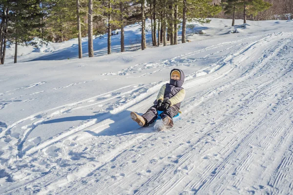 Mulher feliz se divertindo durante rolar pela encosta da montanha no trenó. Esportes de inverno com neve. Pessoas montando um trenó — Fotografia de Stock
