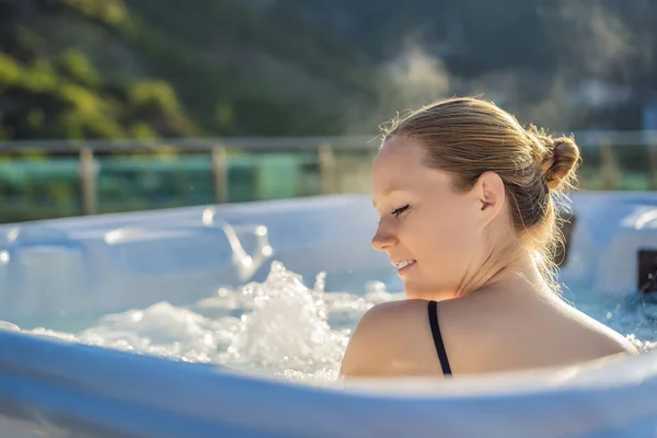 Portrait of young carefree happy smiling woman relaxing at hot tub during enjoying happy traveling moment vacation life against the background of green big mountains — Zdjęcie stockowe