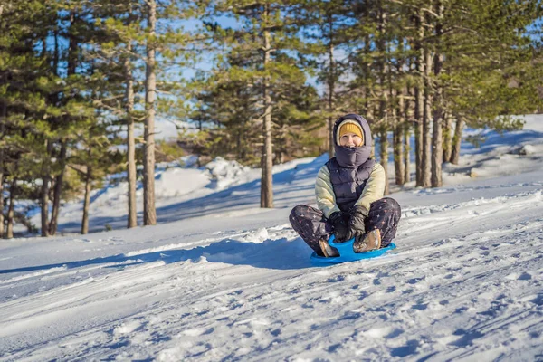 そりで山の斜面を転がる中で楽しい時間を過ごす幸せな女性。雪と冬のスポーツ。人々はそりに乗って — ストック写真