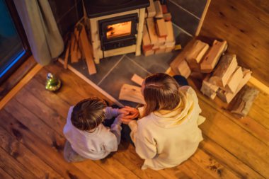 Anne ve oğlu Glamping 'de şöminenin başında vakit geçiriyorlar. Glamping 'deki dağlarda dinlen. Dağ evinde sıcacık şömine.