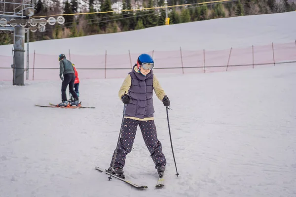 Anne ve oğlu bir eğitmenle kayak yapmayı öğreniyor. Güvenlik kaskı, gözlüğü ve direkleri olan aktif bir çocuk. Küçük çocuklar için kayak yarışı. Aile için kış sporu. Alp okulunda çocuklar kayak dersi alıyor. — Stok fotoğraf