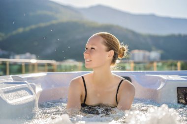 Genç kaygısız mutlu kadının portresi jakuzide rahatlayarak yeşil büyük dağların arka planında mutlu bir tatil hayatı yaşıyor.