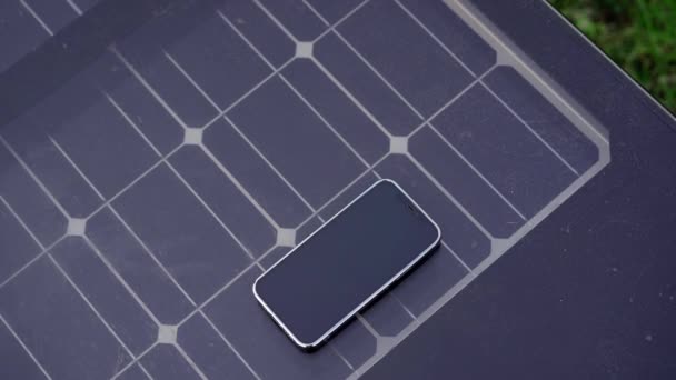 Un banc intelligent avec un smartphone posé dessus. Un banc intelligent a des panneaux solaires sur son dessus et peut charger des périphériques USB gratuitement — Video
