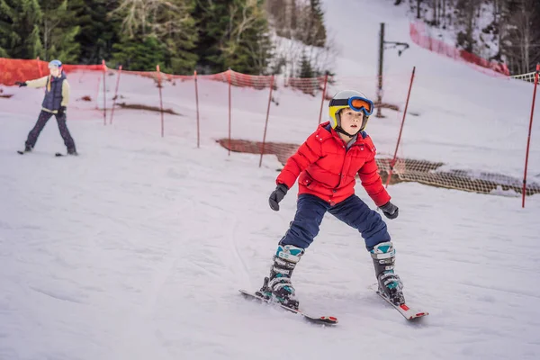 Ski d'enfant en montagne. Enfant tout-petit actif avec casque de sécurité, lunettes et bâtons. Course de ski pour jeunes enfants. Sport d'hiver pour la famille. Cours de ski pour enfants à l'école de ski alpin. Petit skieur de course dans la neige — Photo