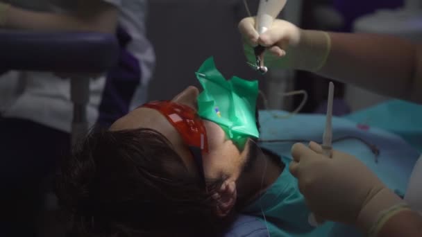 Mulher dentista trata um homem. O processo de remover um nervo de um dente — Vídeo de Stock