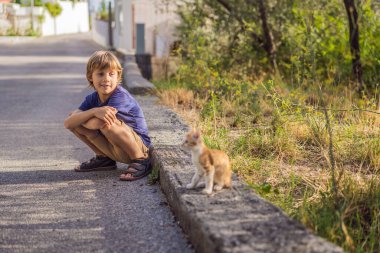 Çocuk yol boyunca bir kedi yavrusuyla dışarıda.