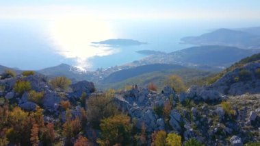Hava görüntüsü. Turist ailesi, baba ve oğul Karadağ 'daki Kosmach Kalesini ziyaret etti. Uzaktan Budva şehrini izleyen bir tepede dikilirken insansız hava aracı üzerlerinden uçuyor.