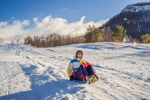 Alegre hombre en trineo por una ladera nevada a toda velocidad —  Fotos de Stock