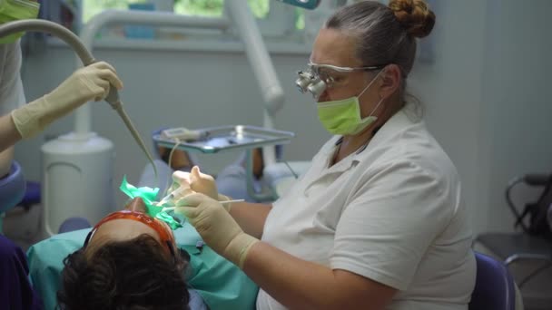 Mulher dentista em um uniforme branco e luvas brancas trata um homem — Vídeo de Stock