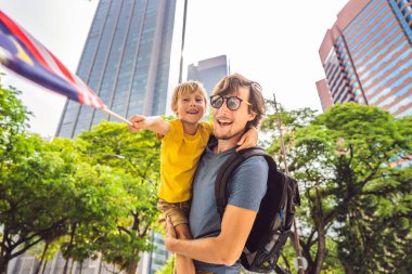 Malezya'da baba ve oğul turistler in anonslarının yanında Malezya bayrağı var. Çocuk konsepti ile seyahat