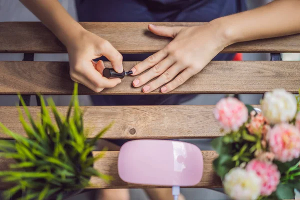 Mulher jovem faz manicure com gel polonês e lâmpada UV em tons rosa — Fotografia de Stock