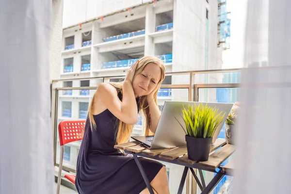 Young woman trying to work on the balcony annoyed by the building works outside. Noise concept. Air pollution from building dust — Stock Photo, Image