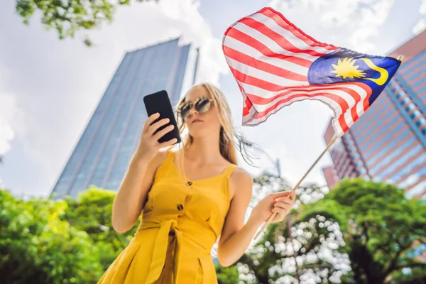 Viagens e tecnologia. Jovem turista com a bandeira de Malásia está olhando para um mapa da cidade em um smartphone para navegação — Fotografia de Stock