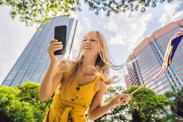 Utazás és a technológia. Fiatal nő turista a zászló Malajzia nézi a Várostérkép egy okostelefon a navigáció — Stock Fotó