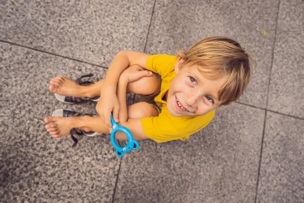 Хлопчик сидить на підлозі і дивиться в збільшувальний келих — стокове фото