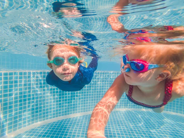 Kinderen plezier spelen onderwater in zwembad op zomervakantie — Stockfoto