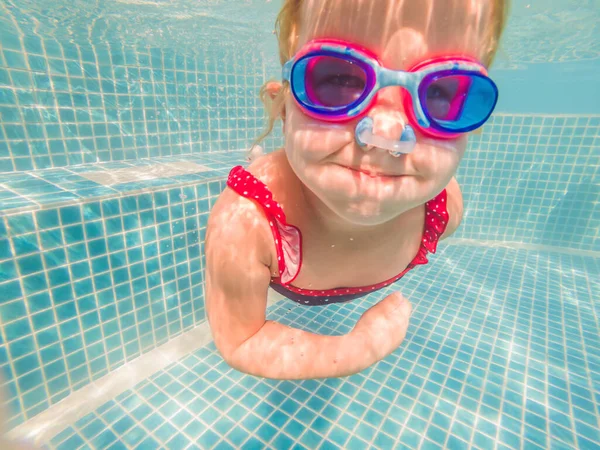 A menina no parque aquático nadando debaixo d 'água e sorrindo — Fotografia de Stock