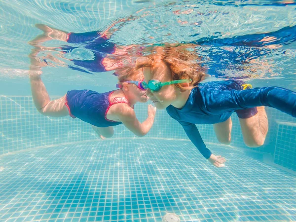 Niños divirtiéndose jugando bajo el agua en la piscina en las vacaciones de verano —  Fotos de Stock