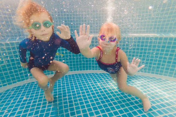 Kinderen plezier spelen onderwater in zwembad op zomervakantie — Stockfoto