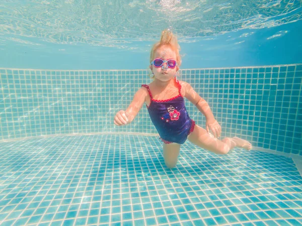 Das kleine Mädchen im Wasserpark schwimmt unter Wasser und lächelt — Stockfoto