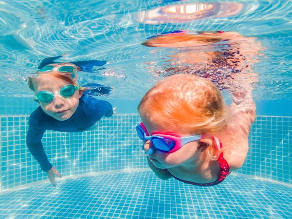 Bambini che si divertono a giocare sott'acqua in piscina durante le vacanze estive — Foto Stock