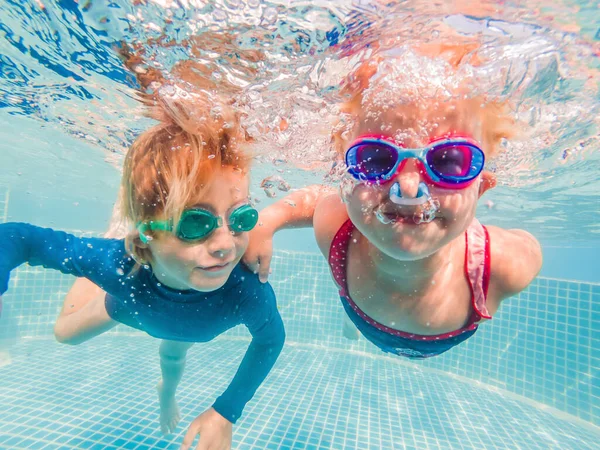 Crianças se divertindo jogando debaixo d 'água na piscina nas férias de verão — Fotografia de Stock