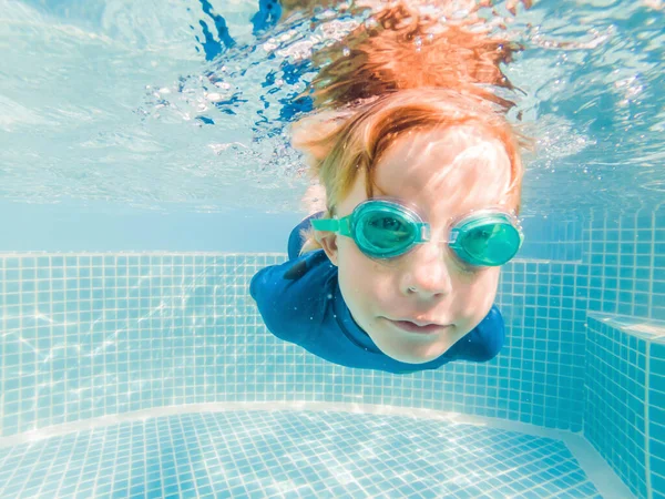 Мальчик веселится, играя под водой в бассейне на летних каникулах — стоковое фото