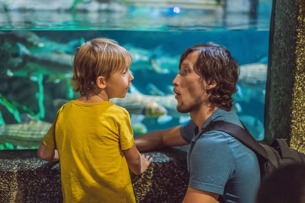 Padre e figlio che guardano i pesci in un acquario a tunnel — Foto Stock