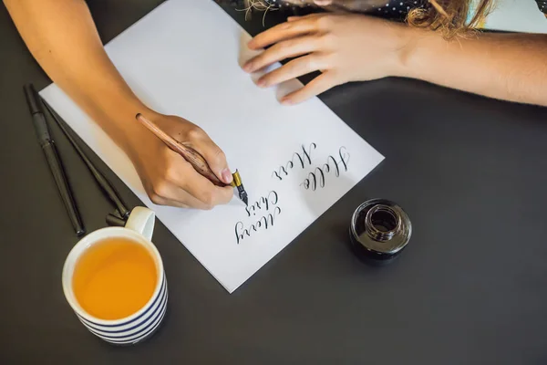 Kalligráfus fiatal nő írja mondat a fehér papíron. Inscribing díszes díszített leveleket. Kalligráfia, grafikai tervezés, betűk, kézírás, létrehozás koncepció — Stock Fotó