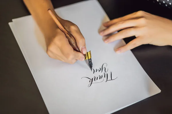 Gracias. Gracias. Calígrafa Joven escribe frase en papel blanco. Inscribiendo letras ornamentales decoradas. Caligrafía, diseño gráfico, letras, escritura a mano, concepto de creación —  Fotos de Stock