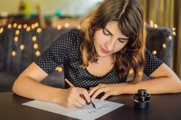 Álom nagy kitűzött célok intézkedni. Kalligráfus fiatal nő írja mondat a fehér papíron. Inscribing díszes díszített leveleket. Kalligráfia, grafikai tervezés, betűk, kézírás, létrehozás koncepció — Stock Fotó