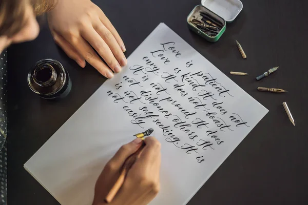 Kalligraaf handen schrijft zin op wit papier. Bijbel zin over liefdesbrieven Inscribing decoratieve ingericht. Kalligrafie, grafisch ontwerp, belettering, handschrift, creatie concept — Stockfoto