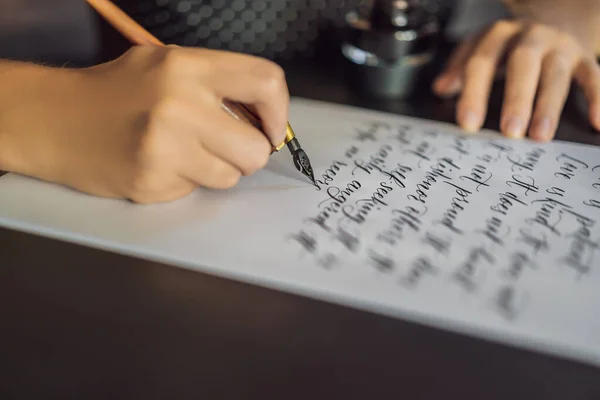 Les mains du calligraphe écrivent des phrases sur du papier blanc. Expression biblique sur l'amour Inscrire des lettres ornementales décorées. Calligraphie, graphisme, lettrage, écriture, concept de création — Photo