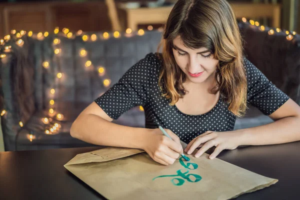 去绿色。书法家年轻女子在白纸上写短语。刻有装饰装饰的装饰字母。书法、平面设计、文字、笔迹、创作理念 — 图库照片