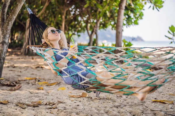 Fiatal nő a tengerparton egy függőágyban egy itallal — Stock Fotó