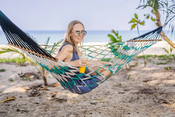 Młoda kobieta na plaży w hamaku z napojem — Zdjęcie stockowe