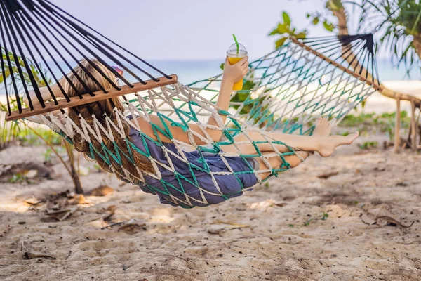 Plajda bir içki ile bir hamak genç kadın