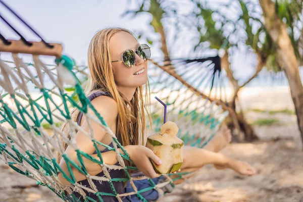 Mujer joven en la playa en una hamaca con una bebida —  Fotos de Stock