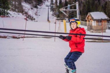 Çocuk eğitim asansörü kullanıyor. Çocuk dağlarda kayak yapıyor. Güvenlik kaskı, gözlüğü ve direkleri olan aktif bir çocuk. Küçük çocuklar için kayak yarışı. Aile için kış sporu. Alp okulunda çocuklar kayak dersi alıyor.