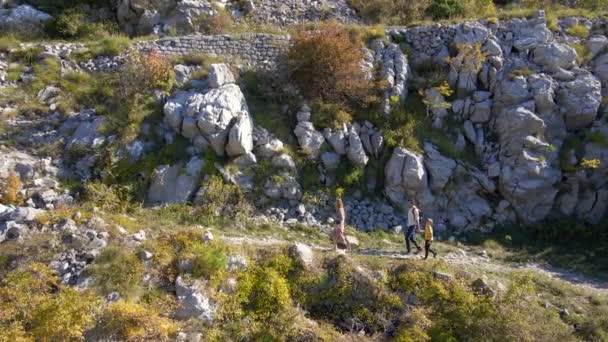 Un disparo aéreo. Dron sigue a la familia de una mujer hombre y su hijo mientras suben la colina hacia la fortaleza de Kosmach en Montenegro. Una antigua fortaleza construida por los austriacos como estructura defensiva — Vídeos de Stock
