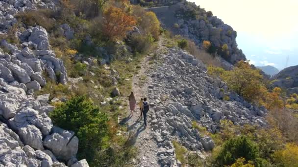 Tiro aéreo. Dron segue a família de um homem mulher e seu filho enquanto eles caminham até a colina em direção à Fortaleza Kosmach em Montenegro. Uma antiga fortaleza construída pelos austríacos como estrutura defensiva — Vídeo de Stock