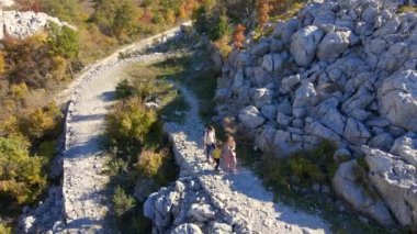 Hava görüntüsü. Dron, Karadağ 'daki Kosmach Kalesi' ne doğru giden bir erkek kadın ve oğullarının ailesini izliyor. Avusturyalılar tarafından savunma amaçlı inşa edilmiş eski bir kale.